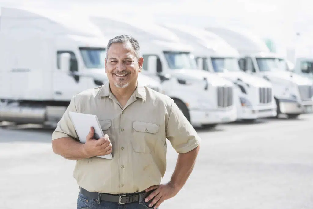 Hispanic man standing in front of semi trucks